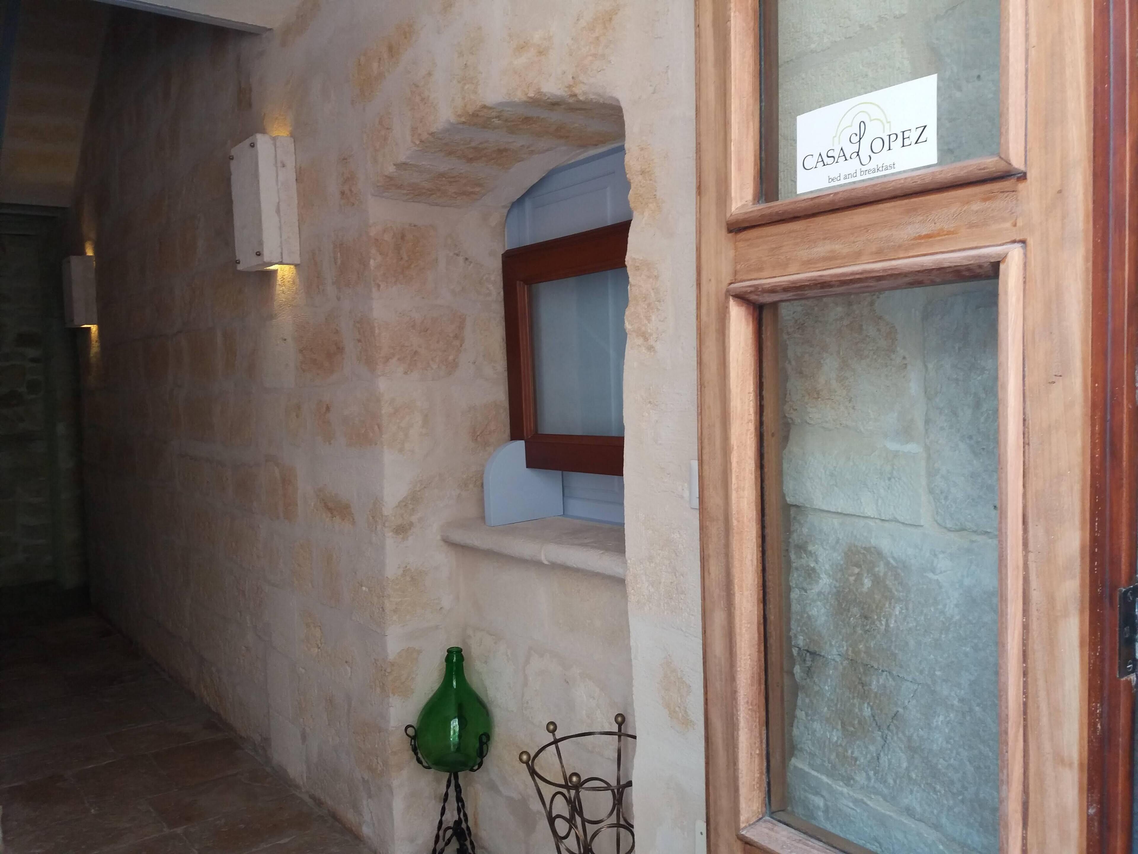 Un muro de piedra con una puerta de madera que dice "CASA LOPEZ bed and breakfast".