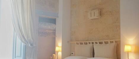 A bedroom with a bed, nightstands, a lamp, and a window with curtains.
