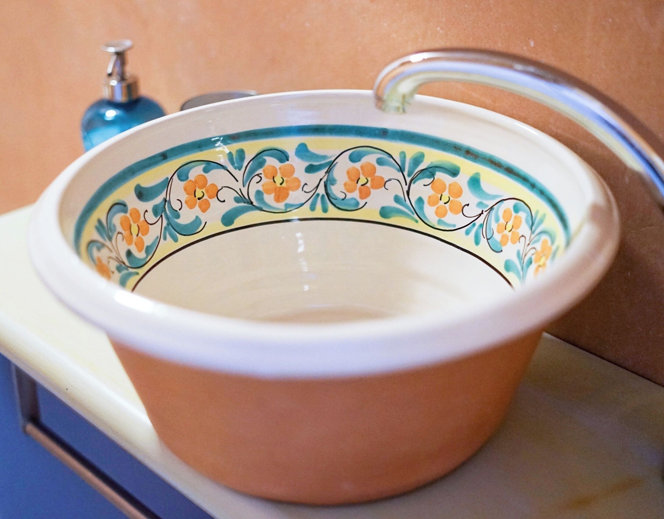 A ceramic basin with a floral pattern and a metal faucet.