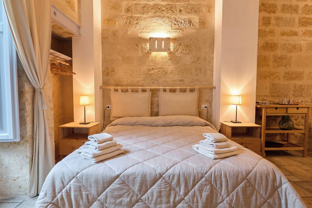 A cozy bedroom with a large bed, two bedside lamps, and a wooden nightstand.