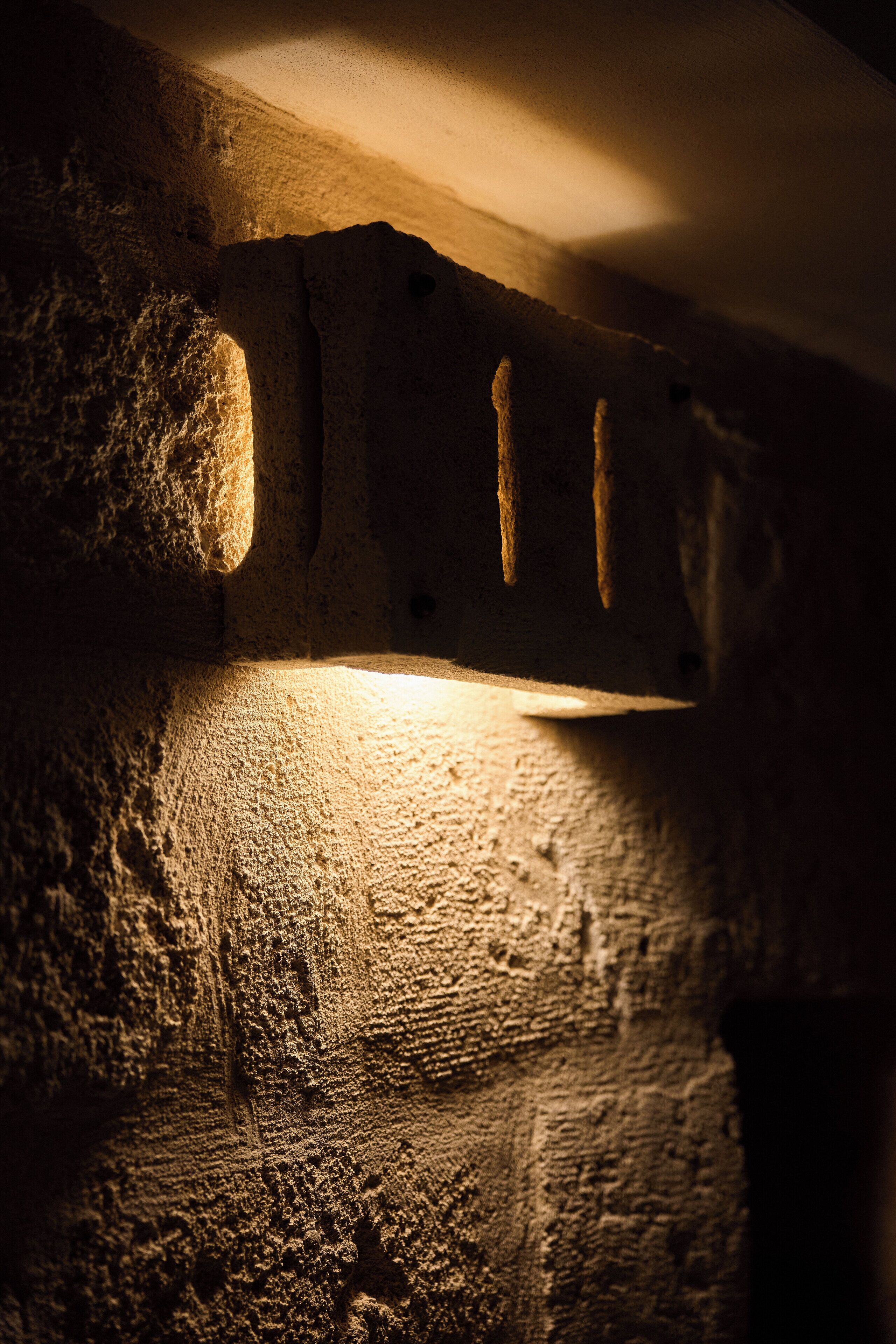 A close-up of a textured stone wall with a light source casting shadows.
