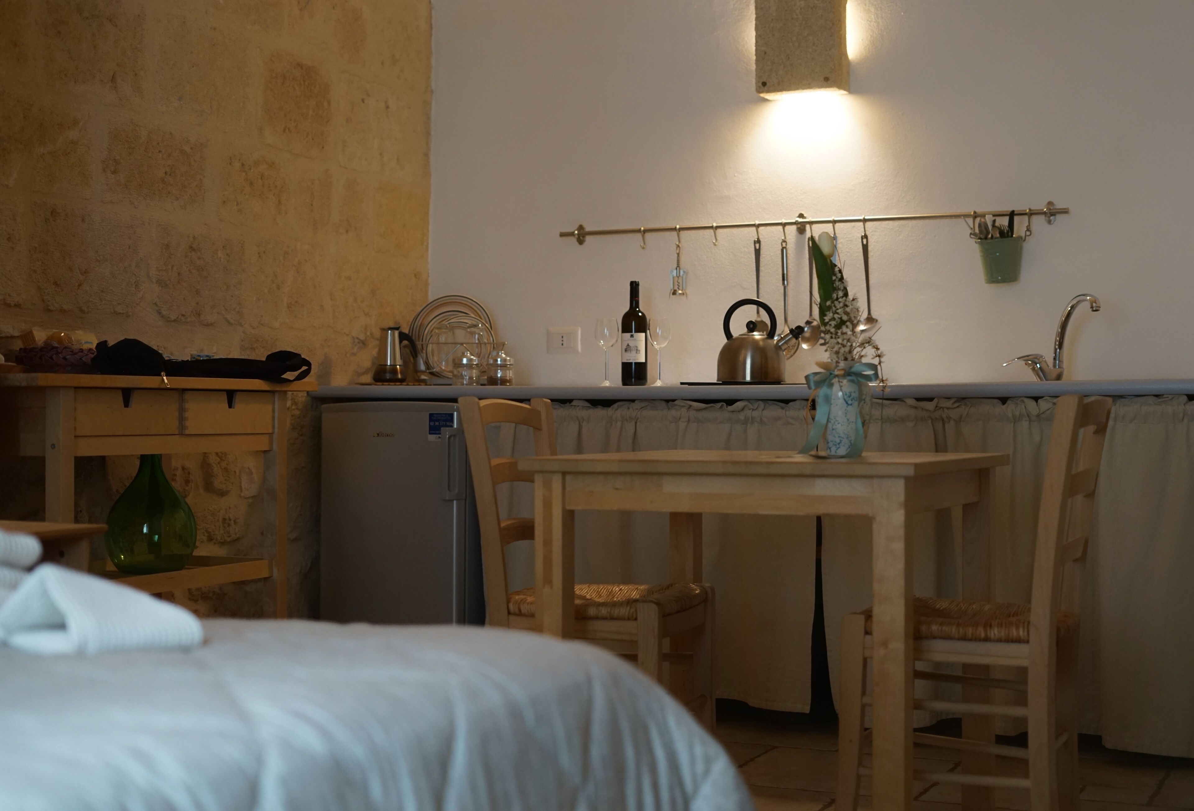 A compact kitchen with a wooden table, chairs, a refrigerator, and a hanging pot rack.