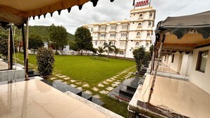 A hotel courtyard with a lawn, a pool, and a building with a sign reading "Dream Resort". - Dreams Resort Udaipur (Udaipur)