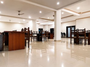 A spacious hotel lobby with a reception desk, multiple seating areas, and ceiling fans.