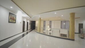 A spacious, well-lit hallway with a polished floor, a decorative column, and a hanging light fixture. - Dreams Resort Udaipur (Udaipur)