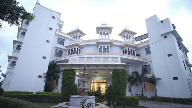 A large, multi-story building with a central courtyard, featuring a fountain and lush greenery. - Dreams Resort Udaipur (Udaipur)