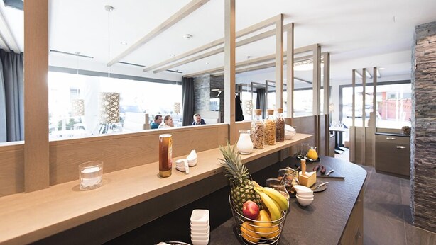 Un espace d’accueil moderne, avec un comptoir en bois, un panier de fruits et un miroir qui reflète la pièce.