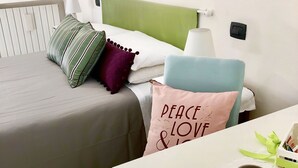 Habitación de hotel ordenada con cama, mesita de noche y una pequeña mesa con una taza y una cuchara.