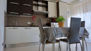 Una cocina moderna con armarios blancos, una campana extractora de acero inoxidable y un comedor con mesa y sillas.