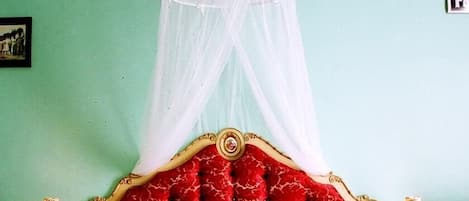 A bed with a red headboard and a white canopy.