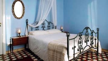 Un dormitorio con cama, mesita de noche, espejo e imagen colgada en la pared.