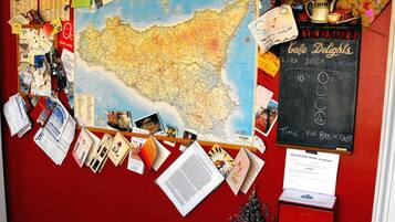 Una bacheca con una mappa, fotografie e una lavagna con i dettagli di un caffè.