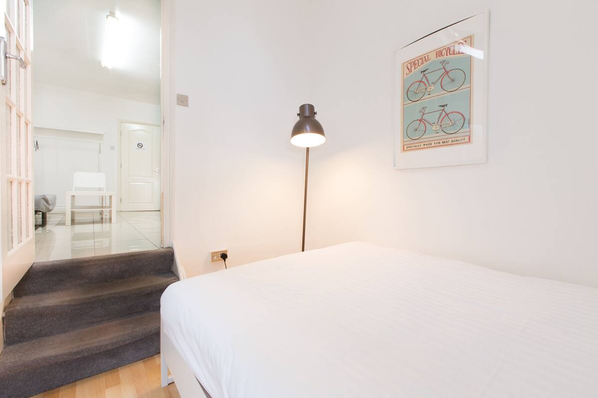 Une chambre à coucher avec un lit, un bureau, une lampe et une affiche encadrée au mur.