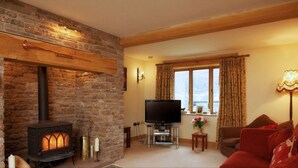 Una sala de estar acogedora con chimenea de piedra, un televisor y un sofá rojo cómodo.