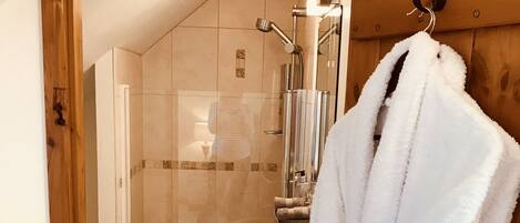 A bathroom with a glass shower enclosure, a white sink, and a wooden door frame.
