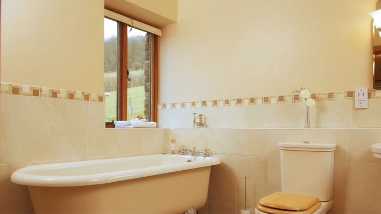 A bathroom with a bathtub, toilet, and a window providing a view of the outdoors.