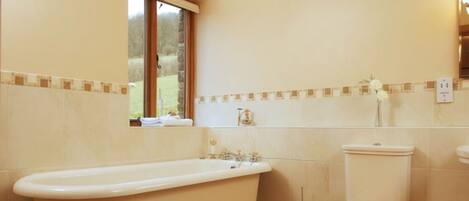 A bathroom with a bathtub, toilet, and a window providing a view of the outdoors.