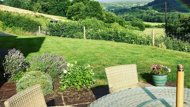 Un jardín con mesa y sillas, un arcoíris y vistas al campo.