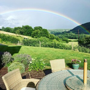 A garden with a table and chairs, a rainbow, and a view of the countryside. - The Celyn (Abergavenny)