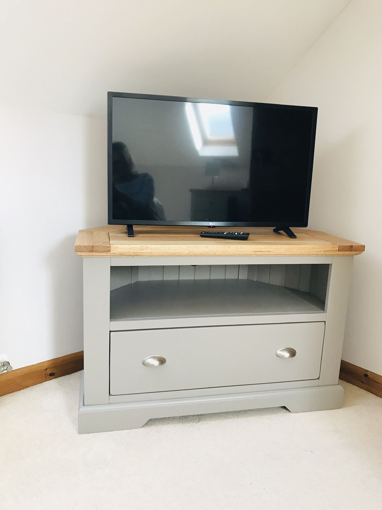Un mueble bajo para televisor con televisor de pantalla plana, un control remoto y un cajón.