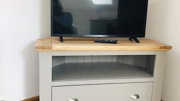 Un mueble bajo para televisor con televisor de pantalla plana, un control remoto y un cajón.
