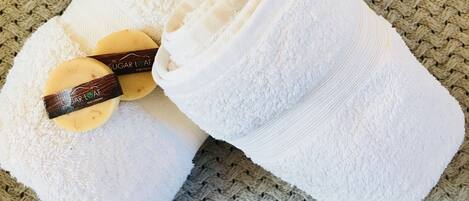 A white towel and a pair of slippers on a textured surface.