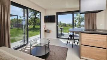 Una cocina moderna con una isla grande, una zona de comedor con mesa de vidrio y un espacio de sala de estar con sofá y mesa de centro de vidrio.