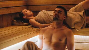 Uma sauna com bancos de madeira e uma pessoa sentada em um deles.