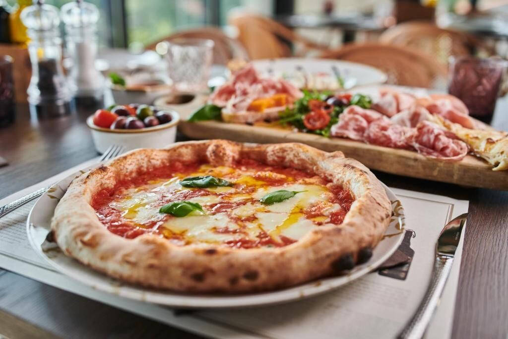 A pizza with tomato sauce, cheese, and basil on a plate.