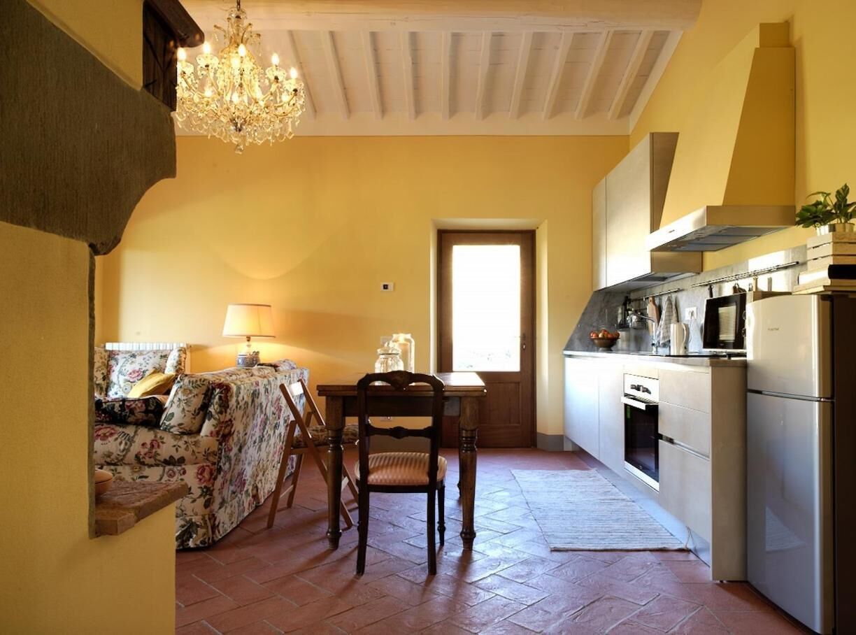 A cozy kitchen with a dining area, featuring a chandelier, a wooden table, and a modern stove.