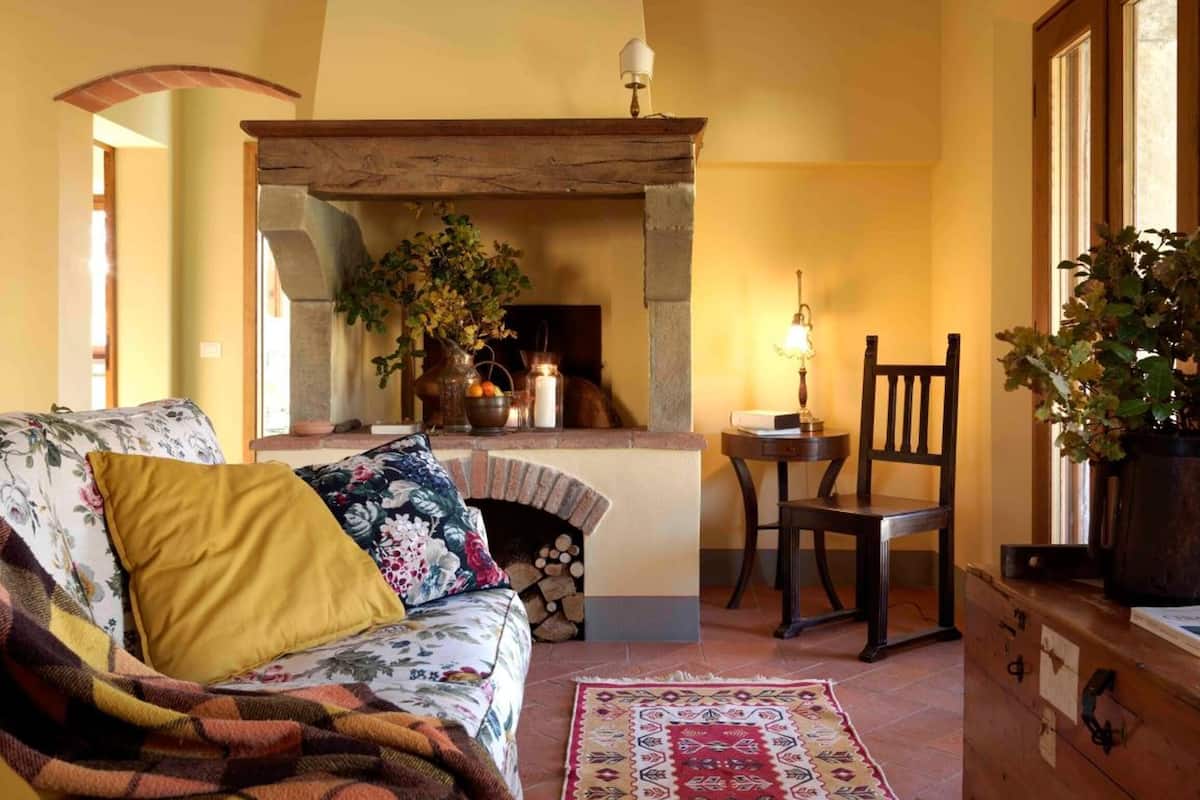 A cozy living room with a fireplace, a sofa, a chair, and a rug.