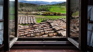Una puerta abierta que da a un viñedo con tejas de arcilla y vistas de colinas ondulantes.