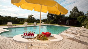 Ein Poolbereich mit Tisch, Stühlen und einem gelben Sonnenschirm.