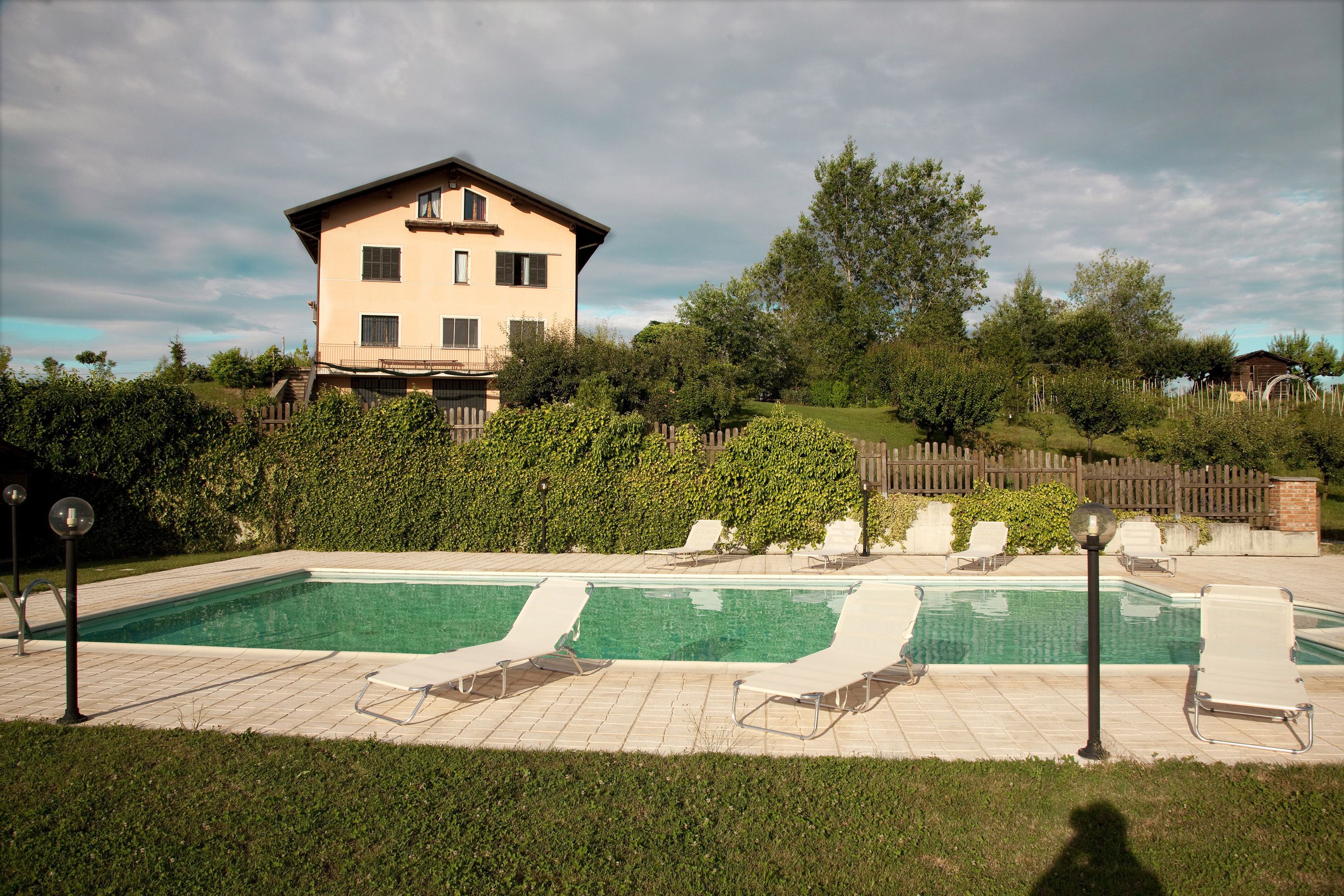 A swimming pool with lounge chairs and a house in the background.