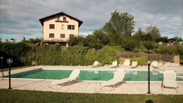 A swimming pool with lounge chairs and a house in the background.