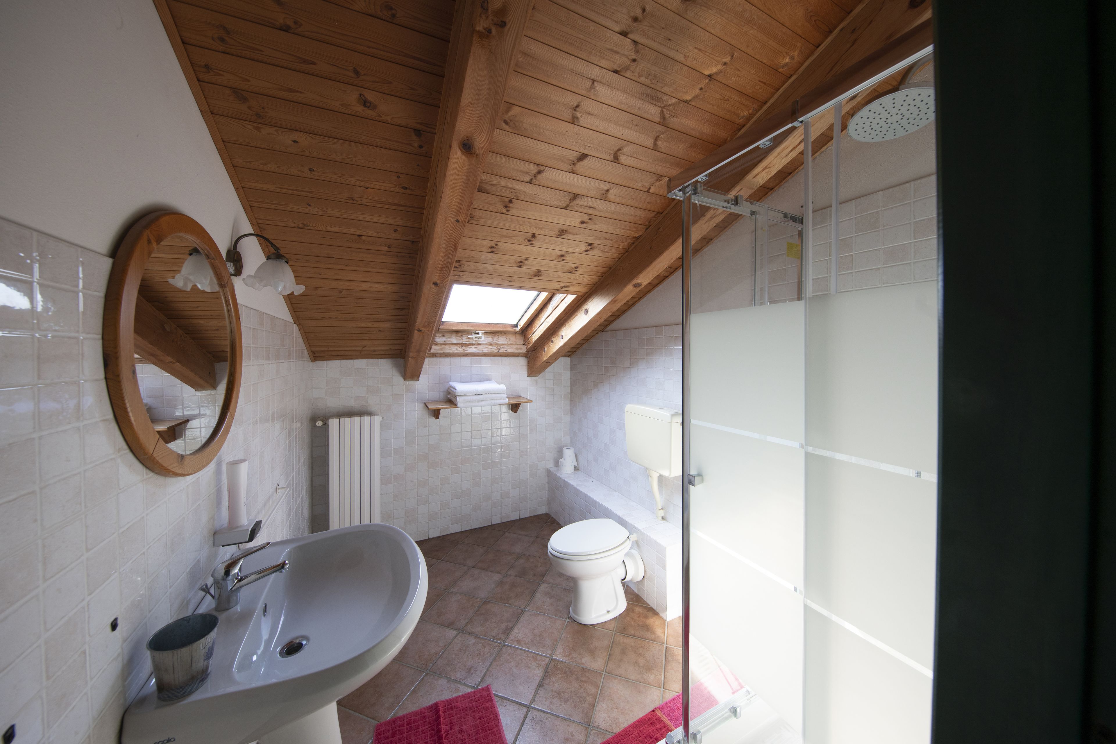 A bathroom with a wooden ceiling, a sink, a toilet, and a shower.