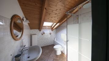 A bathroom with a wooden ceiling, a sink, a toilet, and a shower.