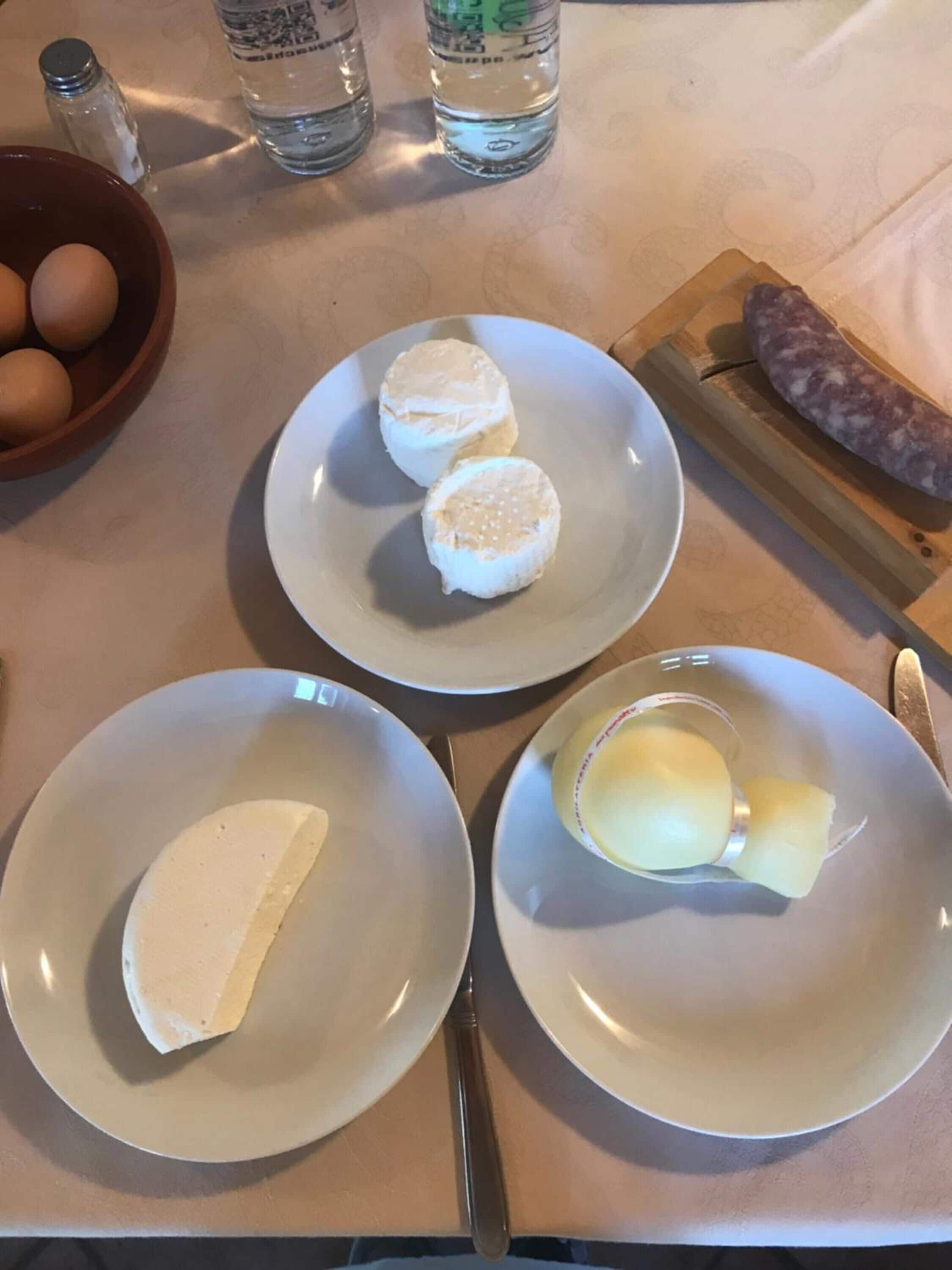 Une table avec des assiettes de fromage, des œufs et une saucisse.
