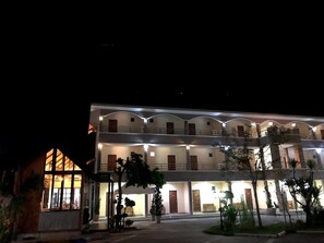 A multi-story hotel with balconies and a well-lit entrance.