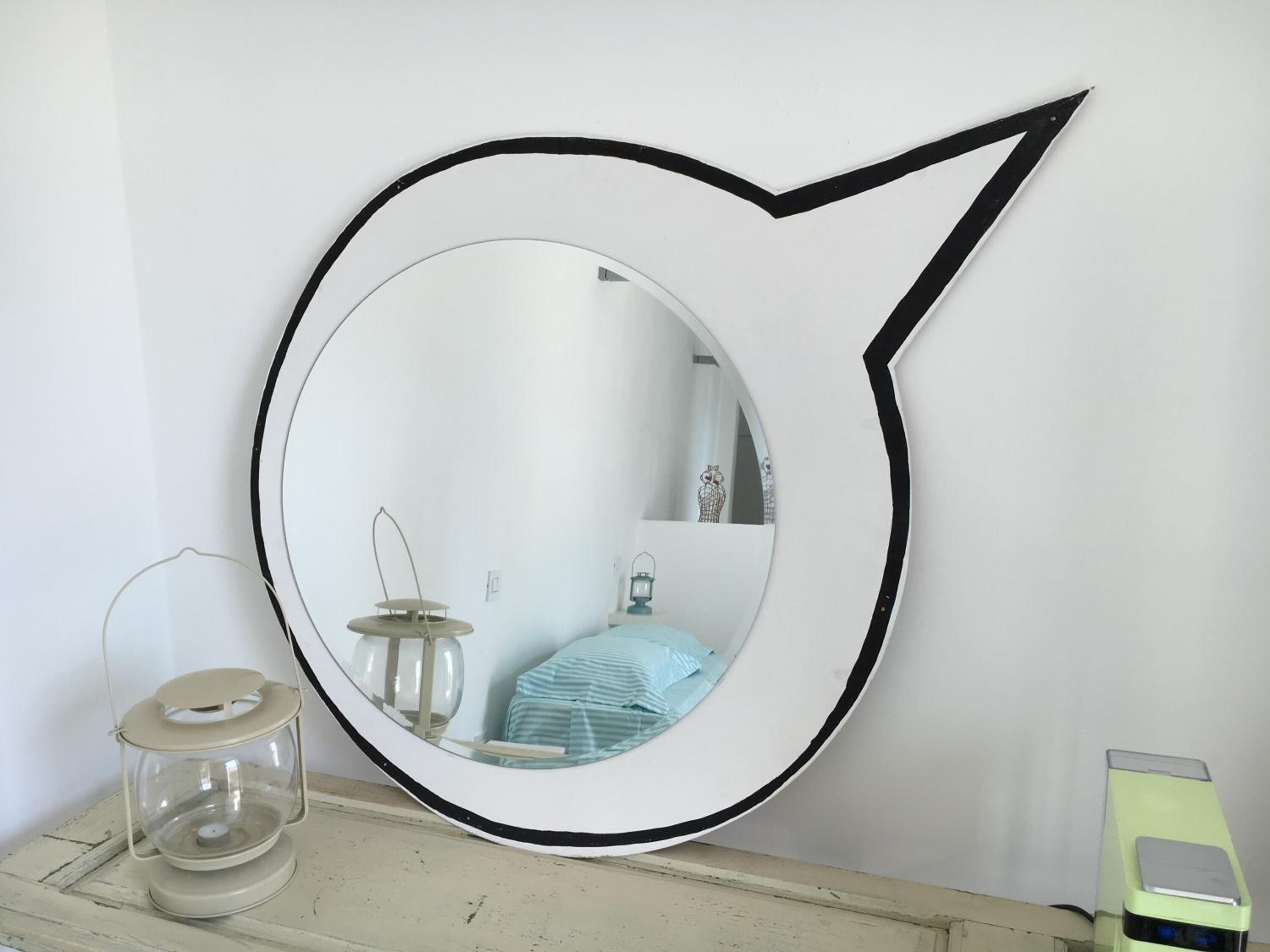 A round mirror with a black frame on a wall.