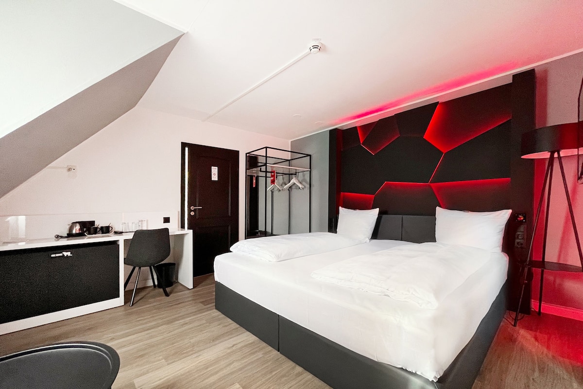 A modern hotel room with a large bed, a desk, and a chair.