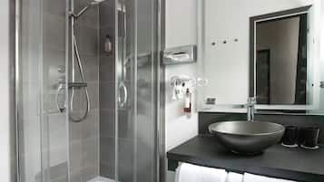 A modern bathroom with a glass-enclosed shower, a black countertop, a large sink, and a mirror.