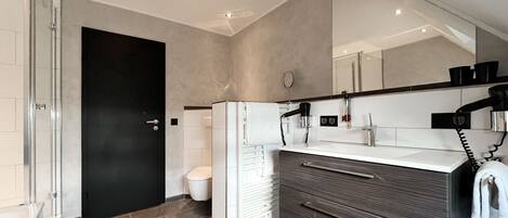 A modern bathroom with a large mirror, a hairdryer, and a toilet.