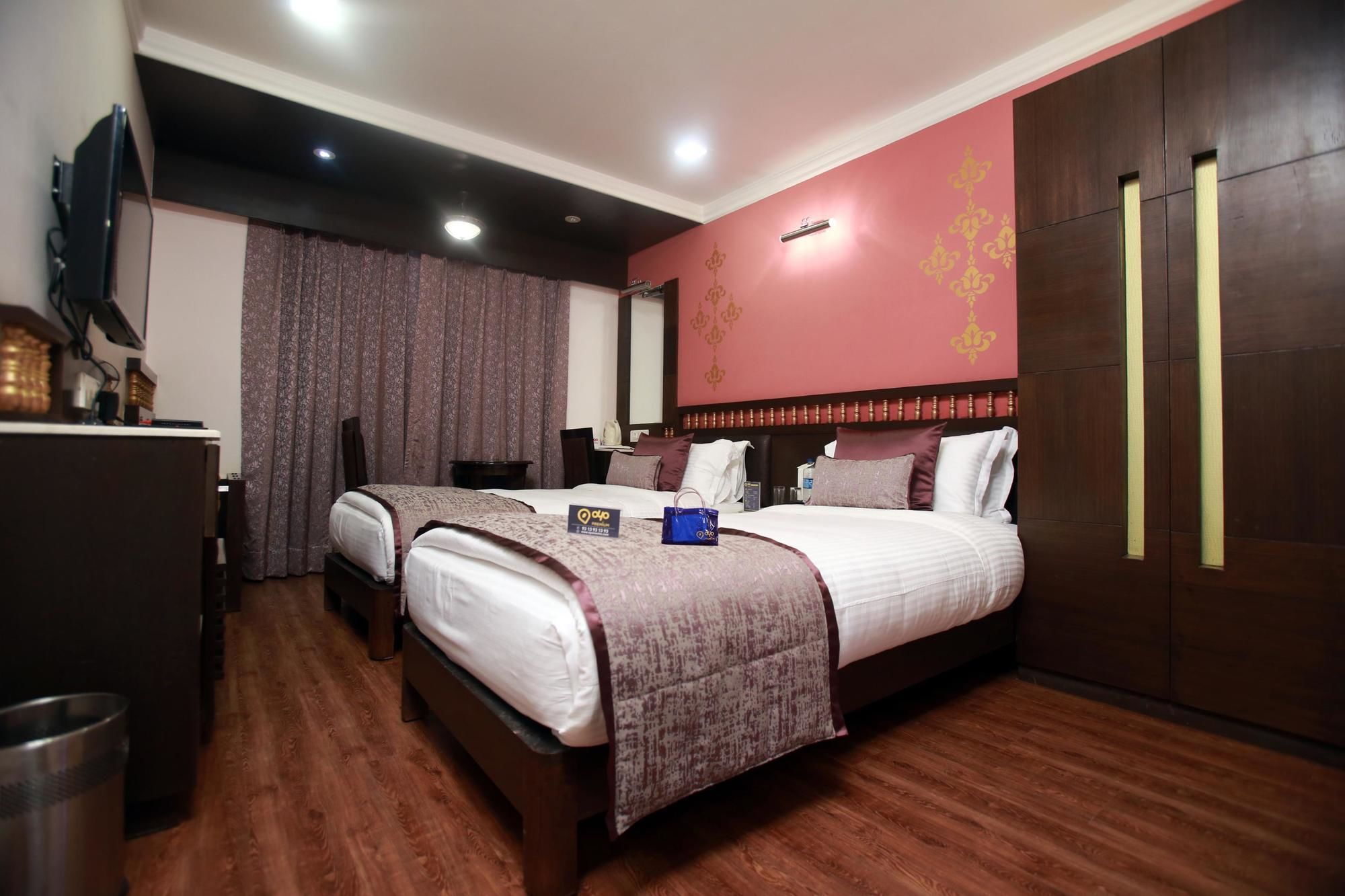 A hotel room with two beds, a wooden floor, a television, and a minibar.
