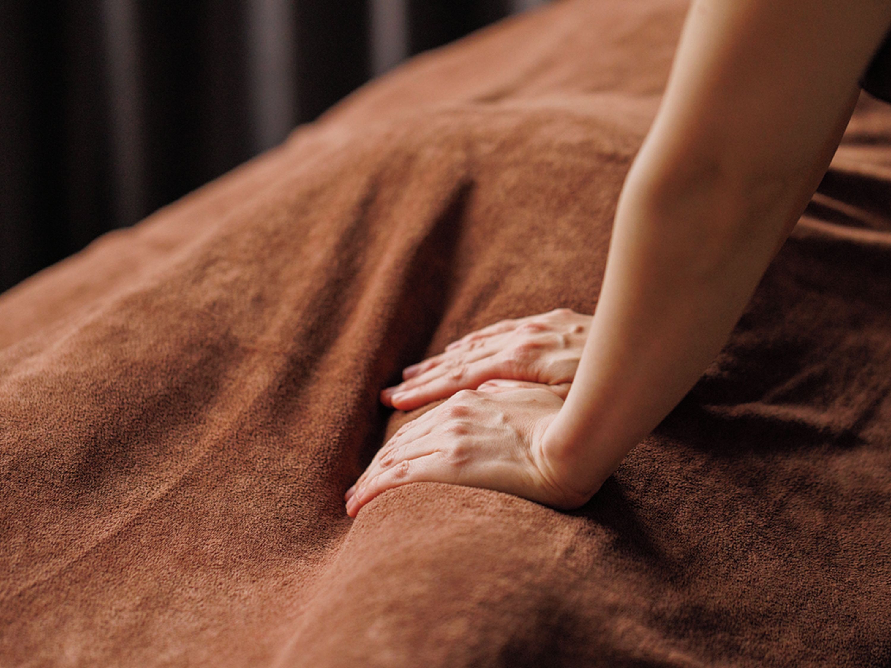 A close-up of hands performing a massage on a textured surface.