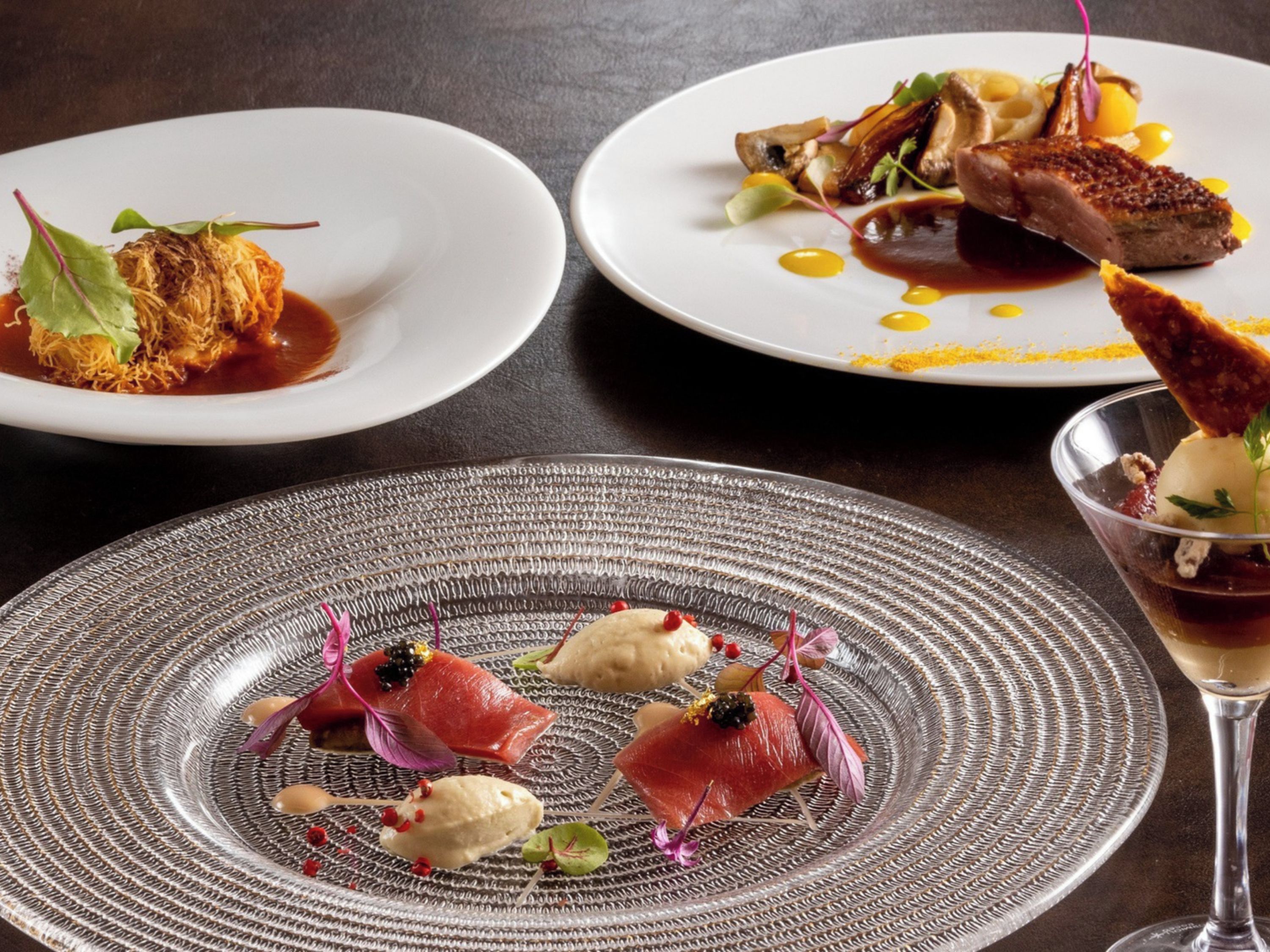 A dining table with three plates of food, each with different dishes.