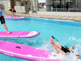 Una piscina con tablas flotantes rosas con la etiqueta 'CAPTAIN STAG'.