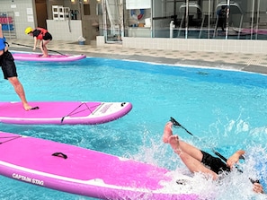 Une piscine avec des planches flottantes roses sur lesquelles est inscrit « CAPTAIN STAG ».