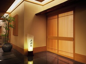 A traditional Japanese interior with tatami flooring, a shoji screen door, and a bamboo plant. - Naspa New Otani (Yuzawa)