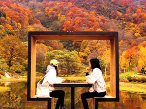 A wooden structure with two benches, a table, and a view of a forested landscape. - Naspa New Otani (Yuzawa)